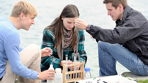 Three students carrying out an experiment on the lake