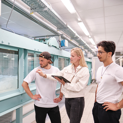 Studierende diskutieren an Kanal in Wasserbaulabor