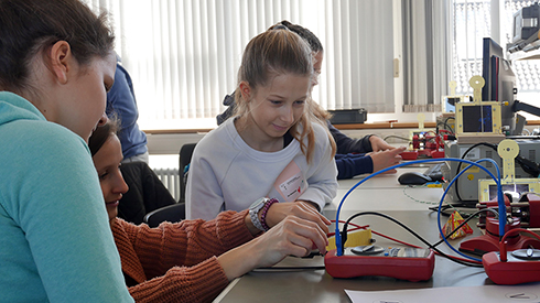 Schülerinnen experimentieren an elektronischen Bauteilen