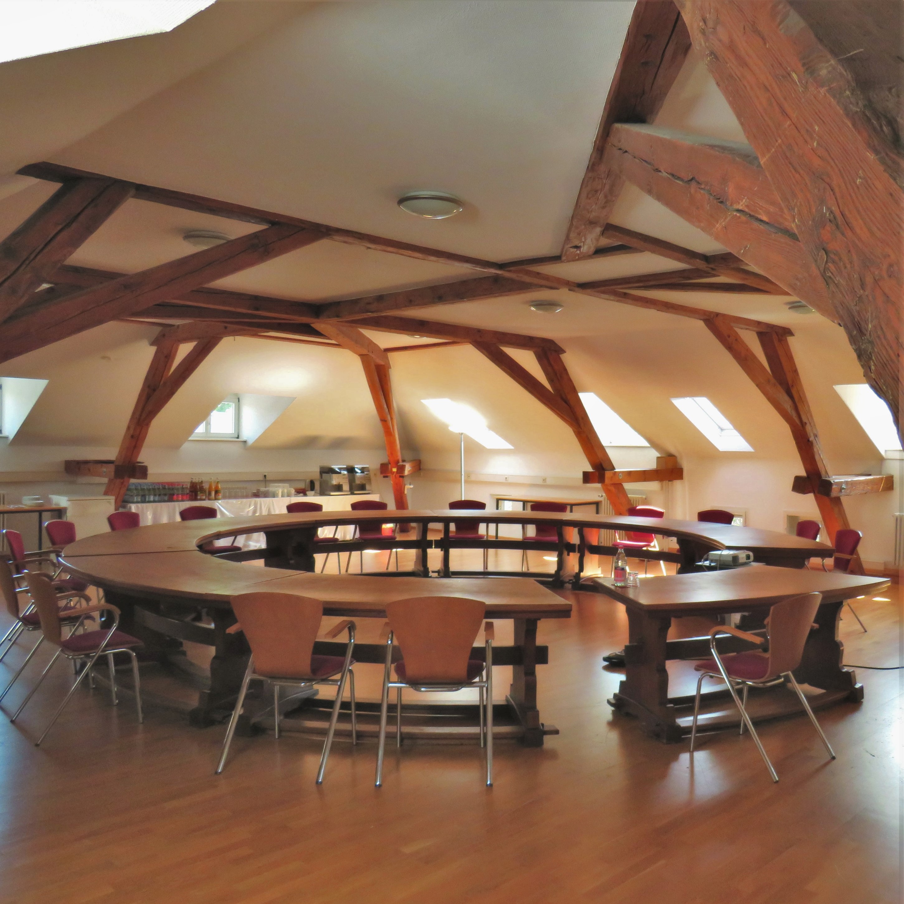 Ein runder Holztisch steht in der Mitte eines Dachgeschossraumes
