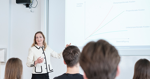 Professorin vor Präsentationsfolie mit Wirtschaftsthema