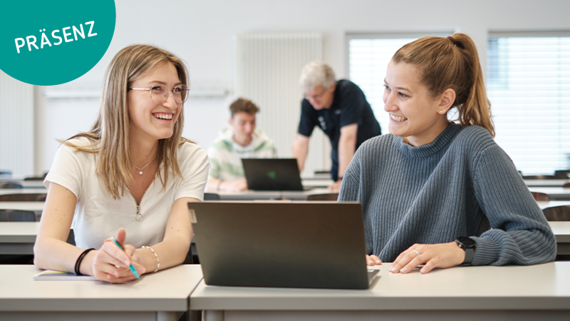 Eine Schülerin und eine Studentin sitzen im Vorlesungssaal und unterhalten sich