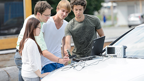 Studierende arbeiten mit Elektrotechnischen Werkzeugen an einem Fahrzeug